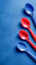 Vibrant Red and Blue Plastic Spoons Arranged on Textured Blue Background Kitchen Utensils Concept