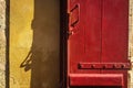 a red door is on a yellow painted wall with a shadow Royalty Free Stock Photo