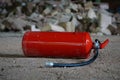 Vibrant red fire extinguisher situated among a pile of grey and white stones