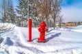 Vibrant red fire hydrant and pole against nature landcsape of snow in winter Royalty Free Stock Photo