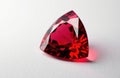 A vibrant red gemstone with a triangular cut resting on a white surface Royalty Free Stock Photo