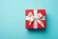 Vibrant red gift box decorated with white satin ribbon and bow, against a pastel blue backdrop Royalty Free Stock Photo