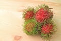 Vibrant Red and Green Fresh Ripe Rambutan Fruits Isolated on Wooden Table Royalty Free Stock Photo