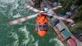 A red helicopter hovering over a body of water, possibly a river or lake, with a backdrop of buildings on the shore. Royalty Free Stock Photo