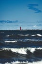 Vibrant red lighthouse seen next to a calm pier in the ocean Royalty Free Stock Photo