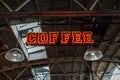 Vibrant red neon coffee sign hanging from the ceiling in industrial style.