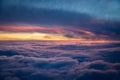 Vibrant red, purple and blue from sunset above the clouds from the window of a plane