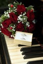 a vibrant red rose bouquet paired with two wedding rings resting atop a classic white organ keyboard Royalty Free Stock Photo