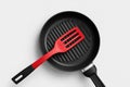 Red spatula resting on a black grill pan ready for cooking tasty meals in a modern kitchen setting Royalty Free Stock Photo