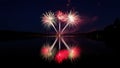 Brilliant fireworks illuminate dark night sky over calm lake Royalty Free Stock Photo