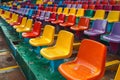 Vibrant rows of multi colored plastic seats fill the stadium grandstand