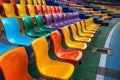 Vibrant rows of multi colored plastic seats fill the stadium grandstand