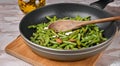 A vibrant scene of healthy meal preparation. Green beans and almonds sautÃÂ© in a pan, stirred by a wooden spoon
