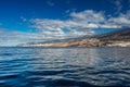 Vibrant scenery and deep-blue waters of the Tenerife west coastline as seen from a yacht. The dormant Teide volcano can be seen in