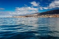 Vibrant scenery and deep-blue waters of the Tenerife west coastline as seen from a yacht. The dormant Teide volcano can be seen in