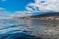 Vibrant scenery and deep-blue waters of the Tenerife west coastline as seen from a yacht. The dormant Teide volcano can be seen in