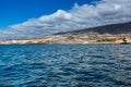 Vibrant scenery and deep-blue waters of the Tenerife west coastline as seen from a yacht. The dormant Teide volcano can be seen in