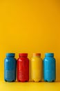 Colorful plastic containers lined up against a yellow background Royalty Free Stock Photo