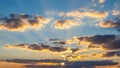 Dramatic sunset sky with golden sun rays bursting through scattered clouds casting warm orange and yellow light Royalty Free Stock Photo