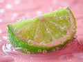 A vibrant slice of lime resting elegantly on a soft pink surface, exuding freshness and simplicity