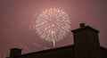 Spectacular Fireworks Bursting in a Crimson Sky Over a City Rooftop at Night, Celebrating an Event Royalty Free Stock Photo
