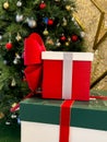 A vibrant stack of festive Christmas gift boxes adorned with ribbons and bows, placed in front of a sparkling holiday tree Royalty Free Stock Photo