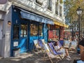 a street scene with some people sitting in chairs outside of storefront