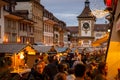 Vibrant street scene at night with people milling around decorated booths at Christmas.