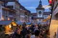 Vibrant street scene at night with people milling around decorated booths at Christmas.