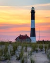 Vibrant summer sunset over a tall stone lighthouse with sand dunes in the foreground. Fire Island NY Royalty Free Stock Photo