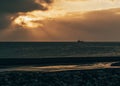 Vibrant sunrise over a fishing boat in Umnak, Alaska, with a beach in the background