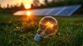 Eco-friendly solar energy concept with glowing light bulb and solar panel at sunset Royalty Free Stock Photo