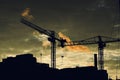 Vibrant sunset illuminates a busy construction site with cranes silhouetted against an orange sky Royalty Free Stock Photo