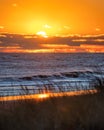 Vibrant sunset over the ocean as the sun dips below the horizon though vibrant clouds