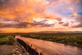 Vibrant sunset over a tranquil river with dramatic clouds and distant mountains. Bolivia Royalty Free Stock Photo