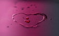 Vibrant water drops heart shape on purple background Royalty Free Stock Photo