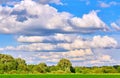 Vibrant wide angle view of a summer countryside landscape and blue cloudy sky