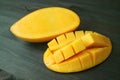 Vibrant Yellow Fresh Ripe Thai Nam Dok Mai Mango Cut in Half on Dark Brown Wooden Table