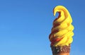 Vibrant Yellow Fruity Flavored Soft Serve Ice Cream Cone Against Sunny Vivid Blue Sky