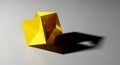 A bright yellow origami cube casting a sharp shadow on a neutral background Royalty Free Stock Photo