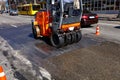 Vibrating orange road roller repairs the road section on a city street Royalty Free Stock Photo