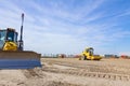 Plate compactor is mounted on road roller to compact soil at construction site Royalty Free Stock Photo