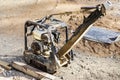 Vibratory rammer with vibrating plate on a construction site. Compaction of soil for further construction work. Close-up Royalty Free Stock Photo