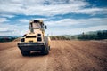 Vibratory Soil Compactor during highway building. Industrial roadworks with heavy-duty machinery