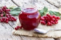 Viburnum fruit jam in a glass jar on a wooden table near the ripe red viburnum berries. Source of natural vitamins. Used in folk Royalty Free Stock Photo