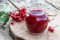 Viburnum fruit jam in a glass jar on a wooden table near the ripe red viburnum berries. Source of natural vitamins. Used in folk Royalty Free Stock Photo