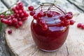 Viburnum fruit jam in a glass jar on a wooden table near the ripe red viburnum berries. Source of natural vitamins. Used in folk Royalty Free Stock Photo