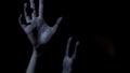 Victim hands stretching out in darkness, begging for help, scary thriller