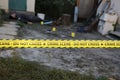 Victim of a violent crime in a backyard of residental house in evening. Dead man body under the yellow police line tape and Royalty Free Stock Photo