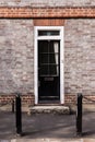 Victorian black external wooden door with glass panels on a classic grey brick wall